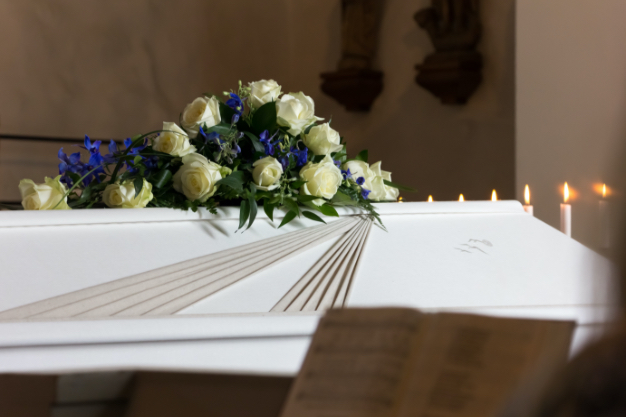 Bouquet of white flowers resting on a white wooden coffin