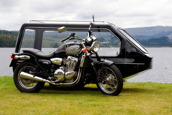 Black motor cycle hearse in front of a lake
