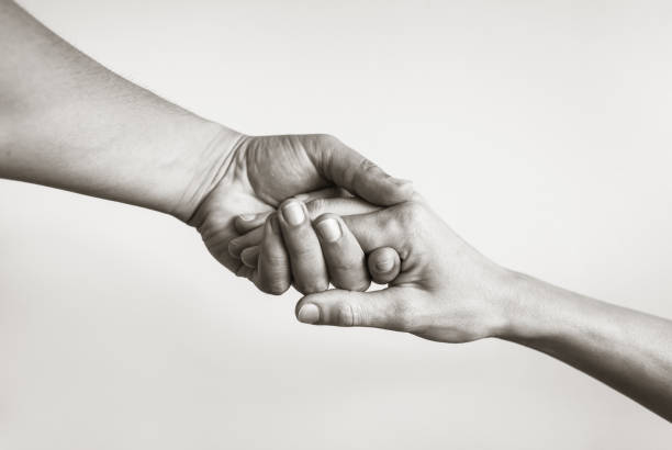 Black and white image of two hands caringly hold one another