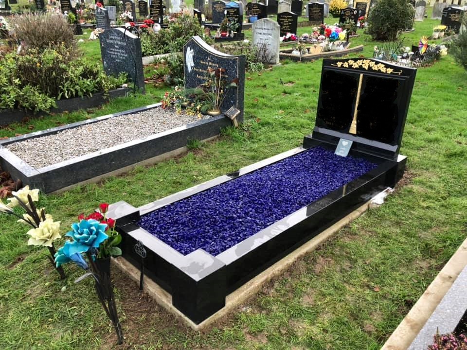 Well maintained black and grey graves with purple and grey stone carefully laid over the top
